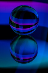 Glass crystal ball on a mirror surface with a blue and purple pattern light painting fractals