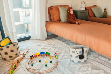 interior of a children's bedroom with toys on the carpet and wooden toy train y headphones
