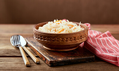 Sauerkraut, fermented cabbage with carrots in bowl on wooden background with copy space. Superfoods for support the immune system.