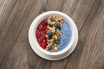 Breakfast smoothie bowl with granola on wooden background