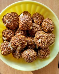 Indian Sweet dish—Sesame laddoo  with cashews in a yellow bowl