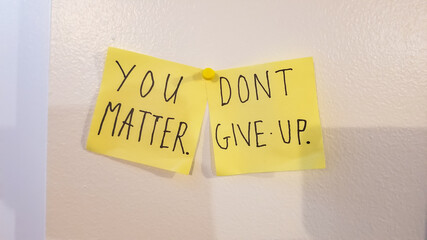 You matter, don't give up encouragement phrase written on two yellow sticky notes posted on a white surface. Positivity message.