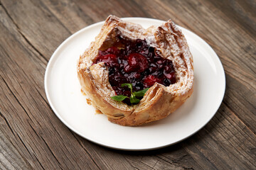 Puff pastry cake with berries on wooden background.