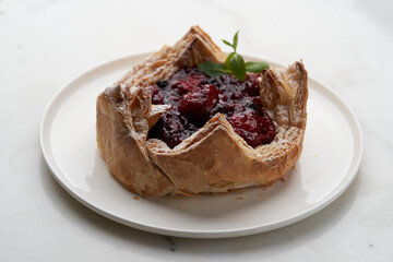 Puff pastry cake with berries on wooden background.