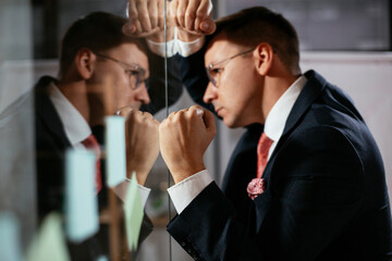 Exhausted businessman in conference room use sticky notes on glass wall. Tired businessman making a business plan.