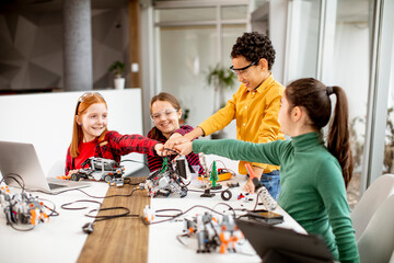 Happy kids programming electric toys and robots at robotics classroom