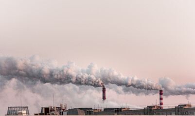 copy space with industrial chimneys with heavy smoke causing air pollution on the pink and gray smoky sky background