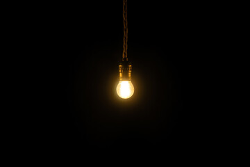 Small vintage glowing light bulb on black background. Electricity concept.