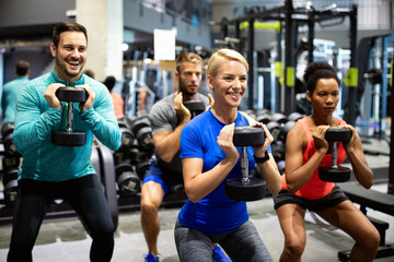 Group of sportive people in gym. Happy fit friends workout, exercise in fitness club