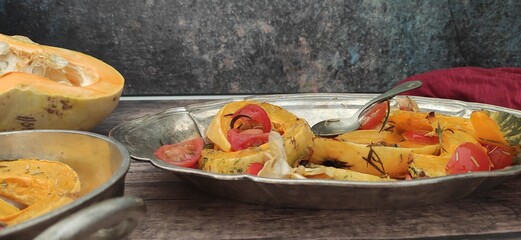 Roasted slices of pumpkin and cherry tomatoes on a silver tray