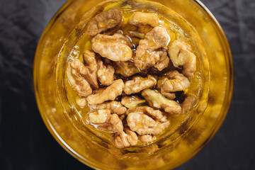 Walnut close-up in honey on a dark background in a glass