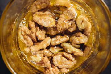 Walnut close-up in honey on a dark background in a glass