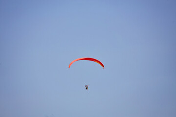 Paragliding in the sky. Paraglider flying in bright sunny day. Beautiful paraglider in flight on a turquise background.