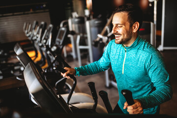 Fit happy man exercising at the gym on a machine