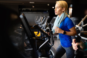 Fototapeta na wymiar Attractive fit young woman using a step machine in the gym