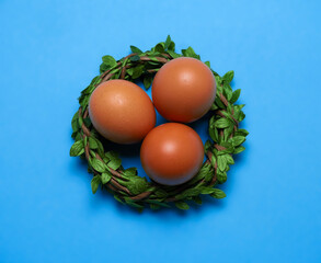 Top view flat lay easter eggs in nest on a blue background. Minimal Easter card.