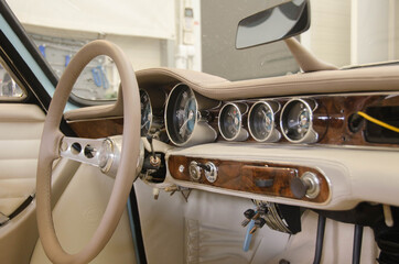 Luxury Race Retro Car Interior With Beige Finish. Speedometer And Tachometer On Dashboard. Car In Workshop