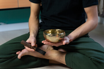 A man plays singing bowl sitting at the floor. Mind and body relationship. Traditional sound...