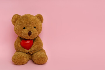 Cute teddy bear with red heart on pink background, space for text. Valentine's day celebration