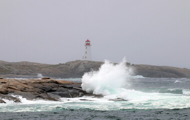Fototapeta na wymiar The iconic Peggy's Cove Lighthouse located in Nova Scotia has withstood many storms and crashing waves on the granite rocks that it stands on.