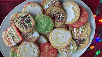 child's hand grabbing Christmas sugar cookie from pile of festive cookies top view