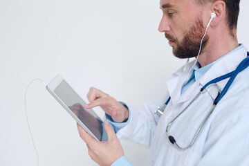 Doctor in earphones pointing at digital tablet while taking online patients