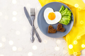Valentines day breakfast with heart shaped fried eggs served on grey plate and yellow napkin