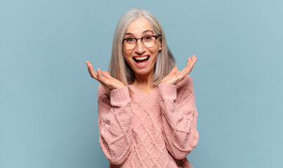 middle age woman feeling shocked and excited, laughing, amazed and happy because of an unexpected...