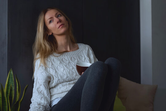 Sch&ouml;ne blonde Frau lehnt nachdenklich an wand