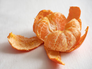 Fresh juicy bright orange tangerines with green leaves on a white cotton tablecloth in the morning light
