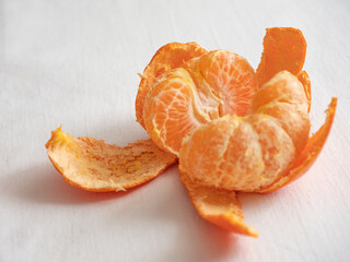 Fresh juicy bright orange tangerines with green leaves on a white cotton tablecloth in the morning light