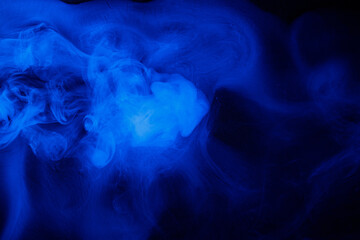 Fototapeta premium Abstract blue smoke moves on black background. Beautiful swirling smoke.