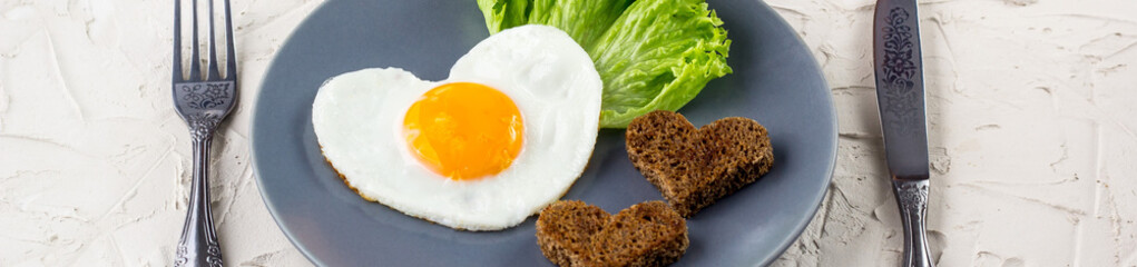 banner of Valentines day breakfast with heart shaped fried eggs served on grey plate