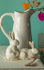 A twig with hearts in a jug and two porcelain hares