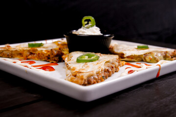 Comida mexicana, com deliciosa culinária mexicana, construção 45º sobre fundo preto. Nachos, burritos, guacamole, tacos, pimenta etc.
