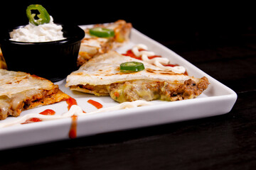 Comida mexicana, com deliciosa culinária mexicana, construção 45º sobre fundo preto. Nachos, burritos, guacamole, tacos, pimenta etc.