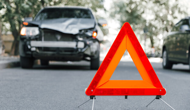 Red emergency stop triangle sign on road in car accident scene. Broken SUV car on road at traffic accident. Car crash traffic accident on city road after collision. Long web banner