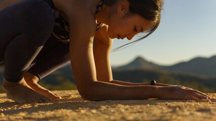 Young good looking woman perform yoga pose on mountain with sun light during sunset