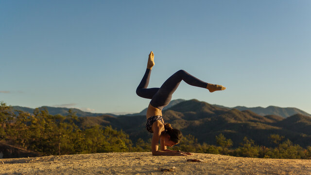 Young good looking woman perform yoga pose on mountain with sun light during sunset
