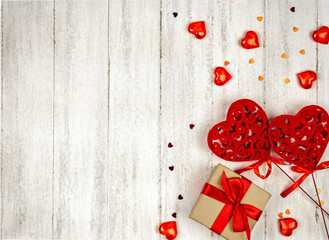 Two large red hearts, a gift and small red hearts on a light background. Festive background with space for text.