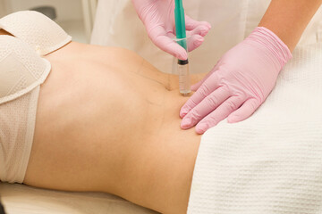 A shot in the stomach. A woman at a cosmetologist receives lipolytics in the stomach. Fat-burning
