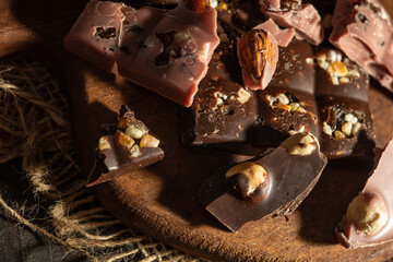 Pieces of pink and dark chocolate on rustic wooden background
