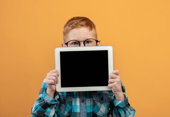 Ginger boy hiding behind digital tablet with empty screen