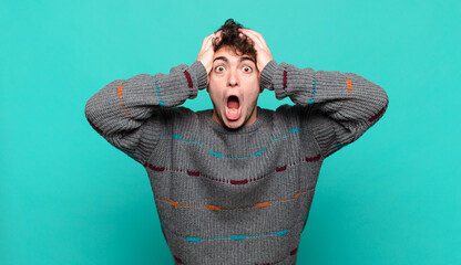 young man feeling horrified and shocked, raising hands to head and panicking at a mistake