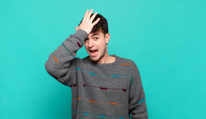 young man raising palm to forehead thinking oops, after making a stupid mistake or remembering,...