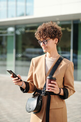 Young serious brunette businesswoman with coffee scrolling through contacts