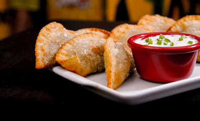 Deliciosos pasteis de carne, camarão, queijo com creme de queijo gorgonzola em recipiente branco...