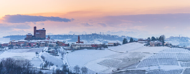 Italy Piedmont: wine yards unique landscape winter sunset, Serralunga d'Alba medieval castle on hill top, the Alps snow capped mountains background, italian heritage panoramic view