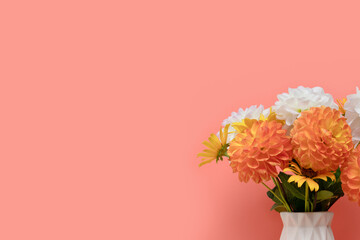 Bouquet of dahlia flowers in vase in front of coral background. Tenderness springtime composition with copyspace.
