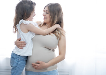 Caucasian happy preschool girl with blonde pregnant mother. hugs Together.